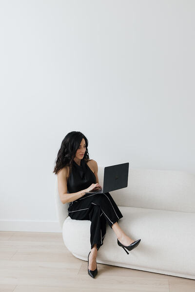 woman sitting on couch with lap top in hand