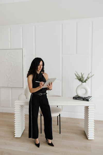 woman standing holding tablet in hand making notes